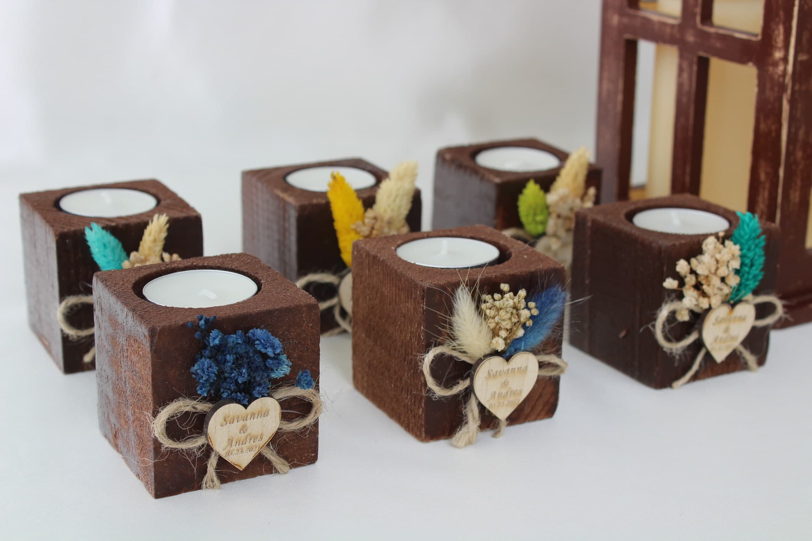 Six wooden tealight favours with dried flowers and heart tags reading Savannah and Andrew 10.10.2023