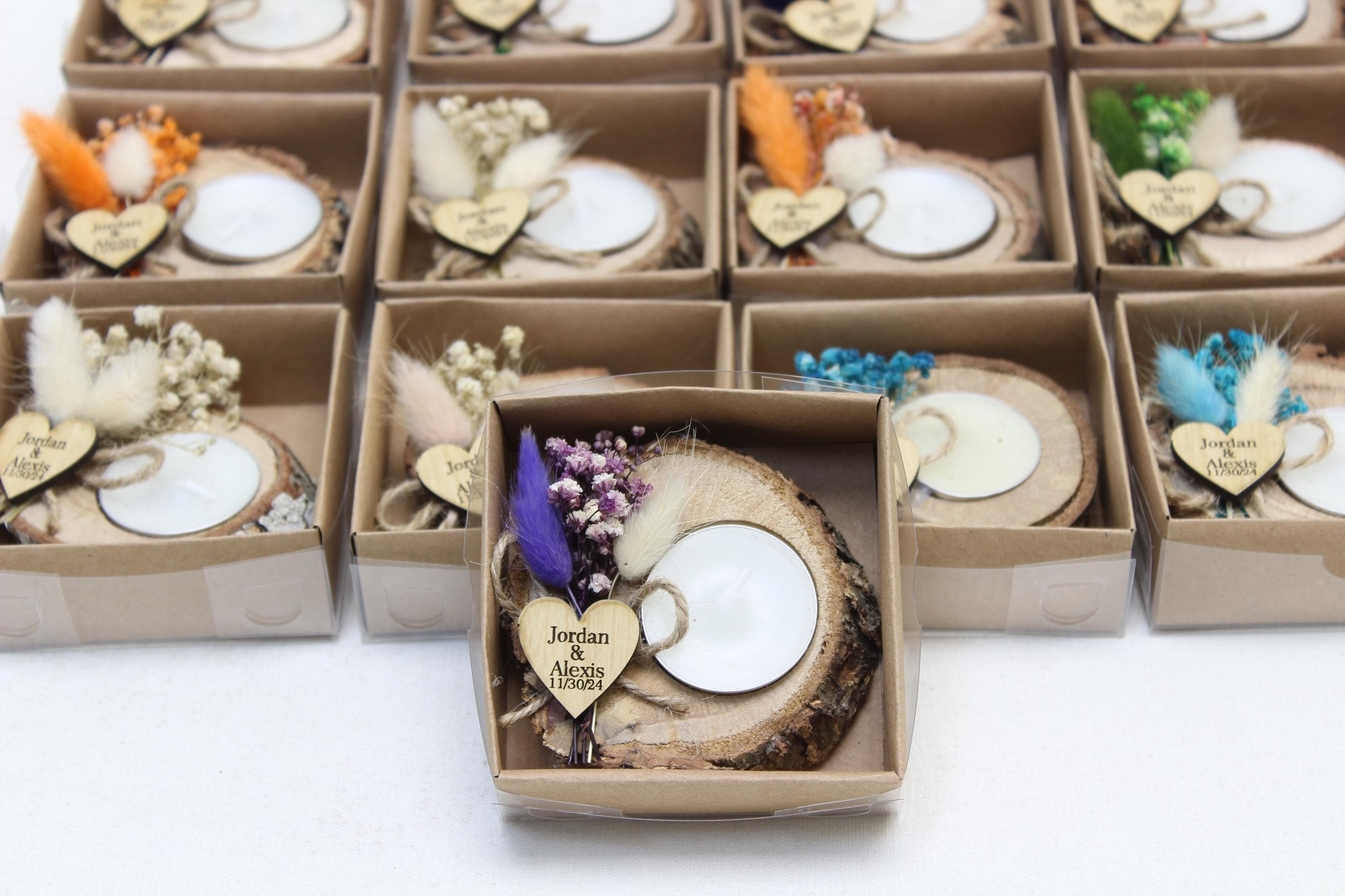 Rows of boxed wooden slice tealight holders with white candles, dried flowers and engraved heart tags