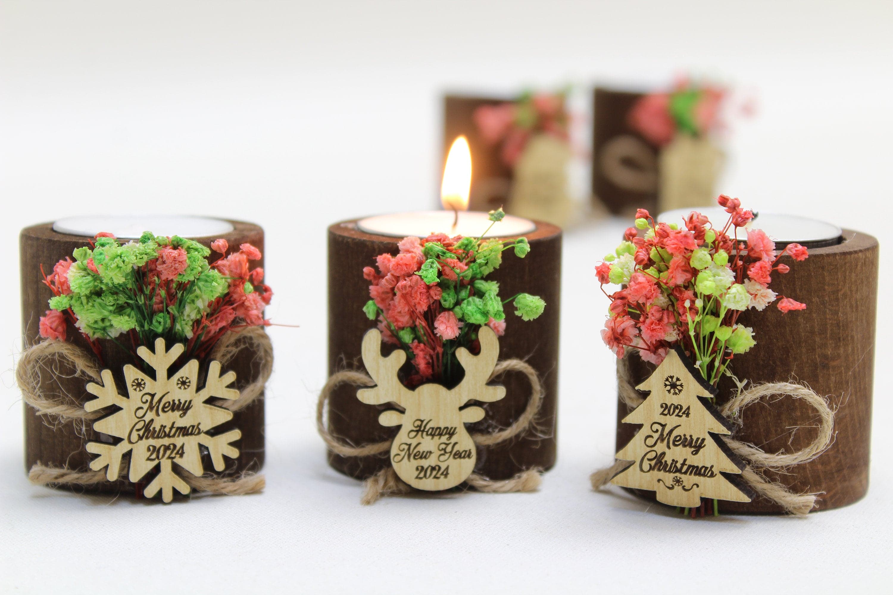 Three wooden tealight holders with dried flowers and engraved snowflake, reindeer and Christmas tree tags
