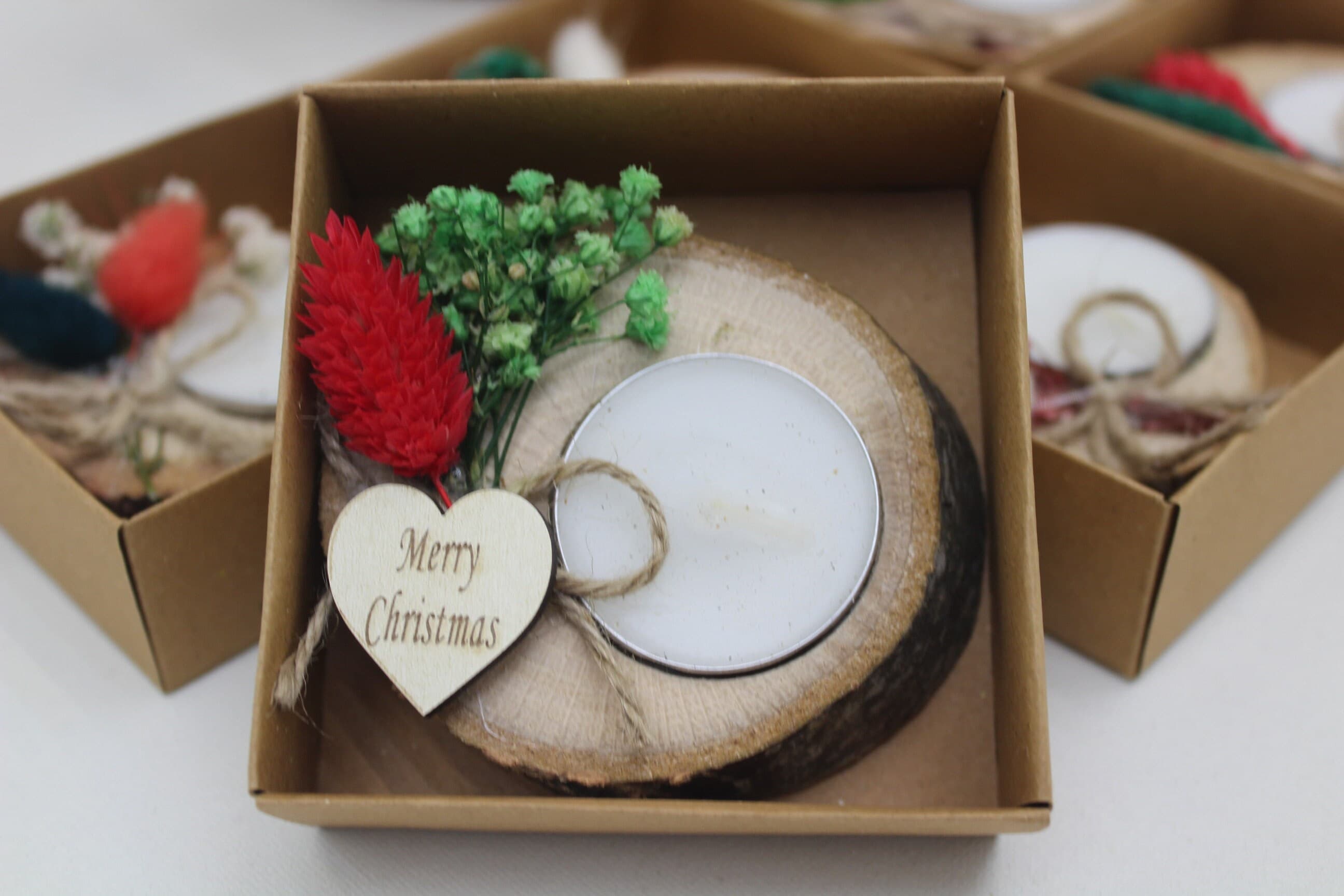 Wood slice tealight holder with a white tealight, red and green dried flowers and a heart-shaped Merry Christmas tag
